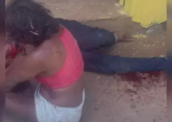 Mulher ficou sentada ao lado do marido após atacá-lo (Foto: Reprodução | Redes sociais)