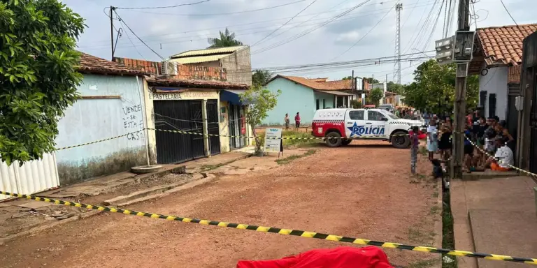 A imagem mostra moradores no local do crime, que está isolado, e o corpo da vítima coberto por um lençol vermelho.