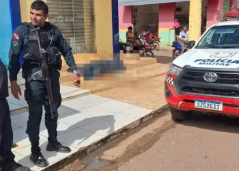 A imagem em destaque mostra policiais e uma viatura da PM perto do corpo, que aparece coberto por um saco preto atrás dos agentes. (Foto: Reprodução | Correio de Carajás)