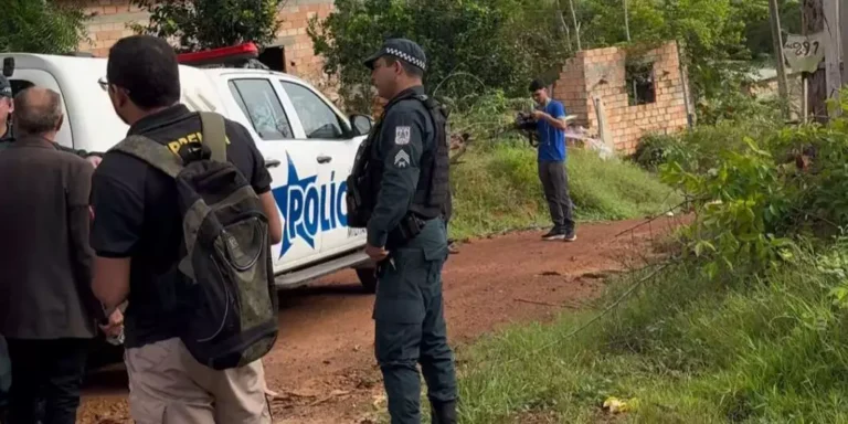 A imagem em destaque mostra um policial militar, uma viatura da corporação e outras pessoas onde o crime ocorreu. (Foto: Reprodução | Portal Giro)