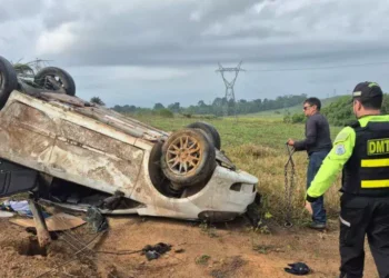 A imagem em destaque mostra um agente de trânsito e um outro homem próximos ao carro capotado. (Foto: Reprodução | Correio de Carajás)