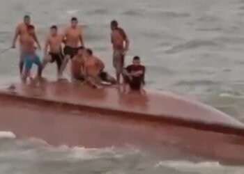 Pescadores ficaram em pé e sentados no casco do barco enquanto tripulantes de outra embarcação tentavam resgatá-los. — Foto: Reprodução / Redes sociais