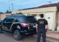 A imagem em destaque mostra um policial federal próximo a uma viatura da instituição e a um dos locais alvos dos mandados. (Foto: Divulgação | Ascom PF)